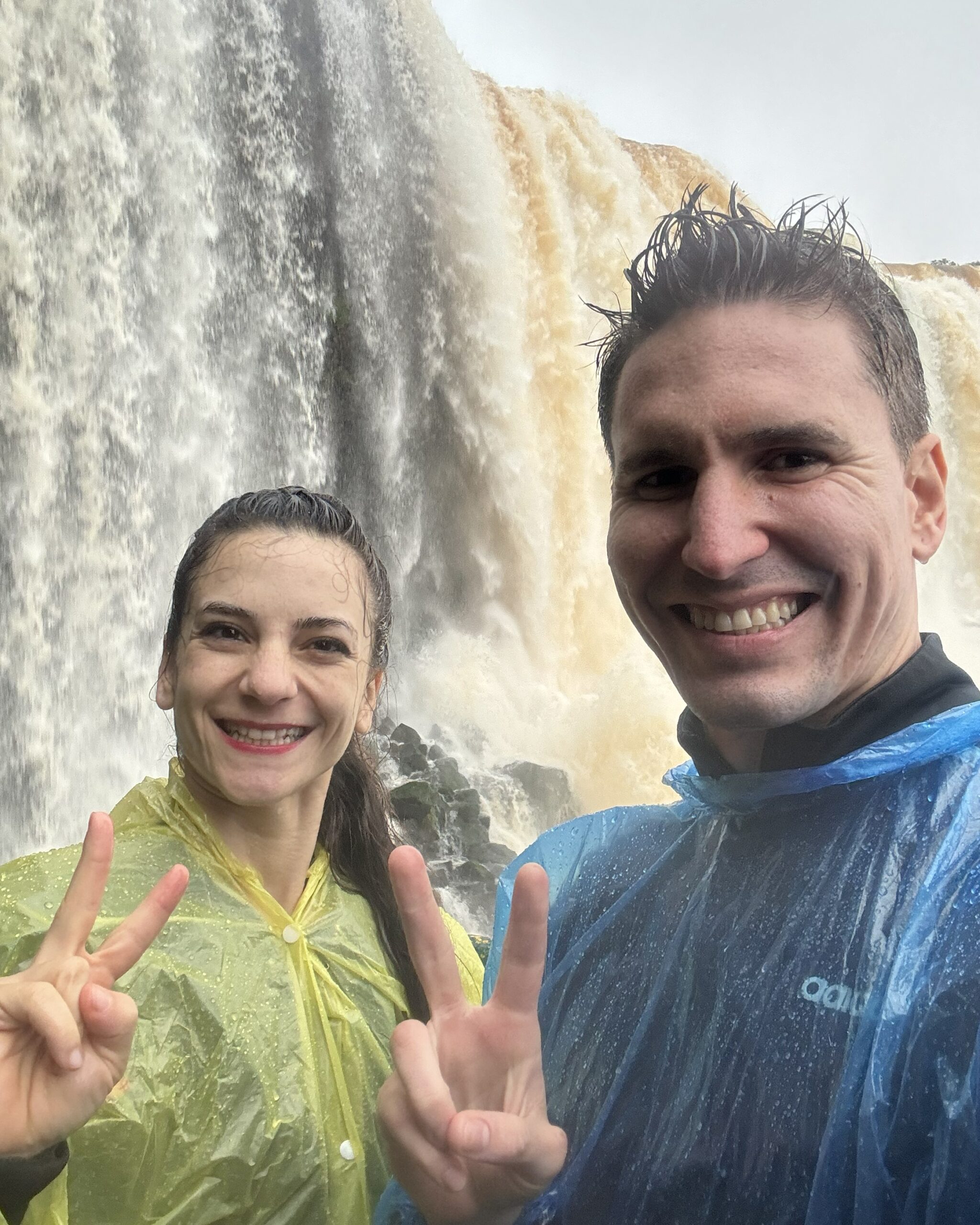 Haha Nomads founders celebrating at a waterfall while traveling